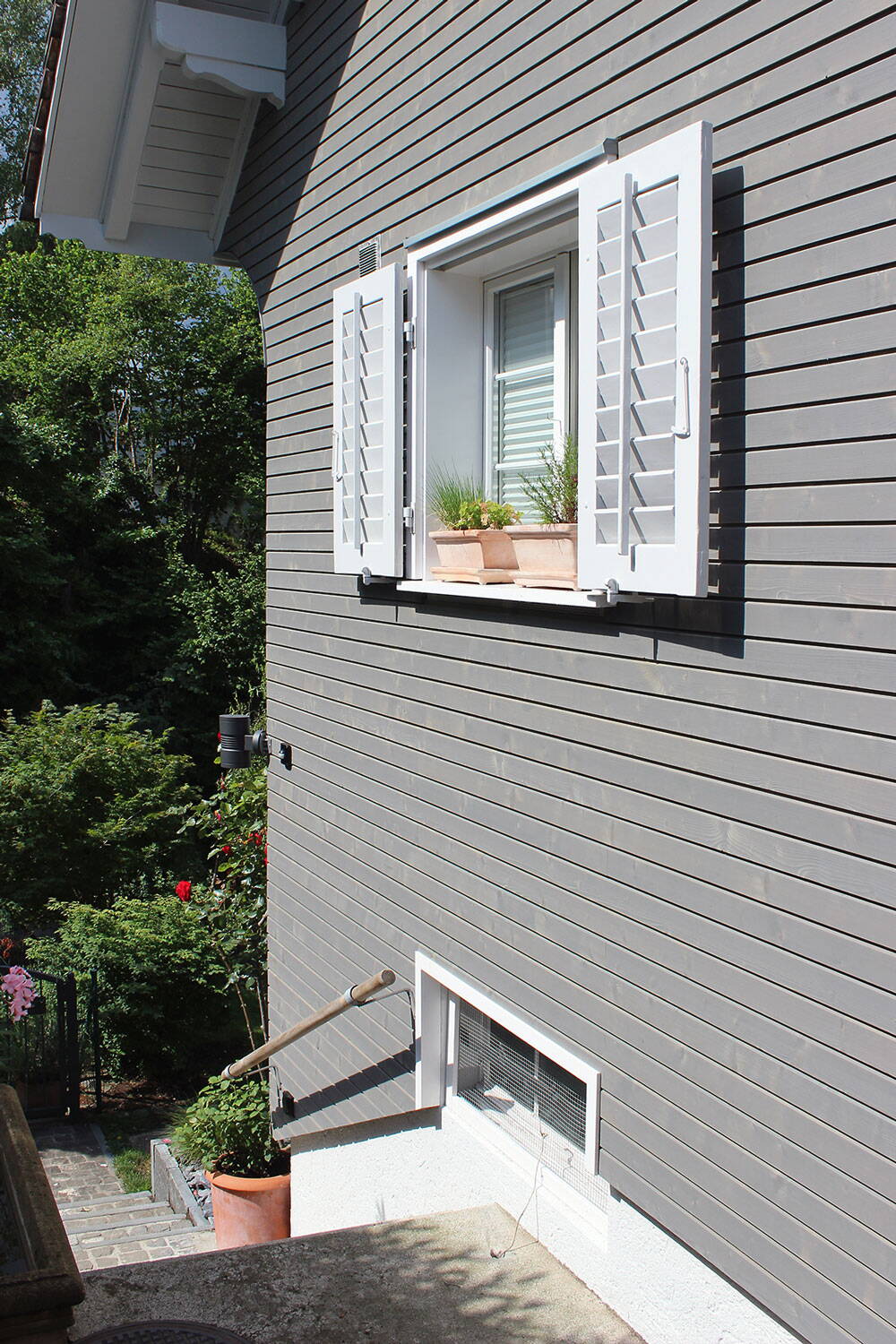 Einfamilienhaus, Stäfa Ausschnitt der fertigen grauen Aussenfassade aus Holzlatten, Fenster mit weissen Fensterläden