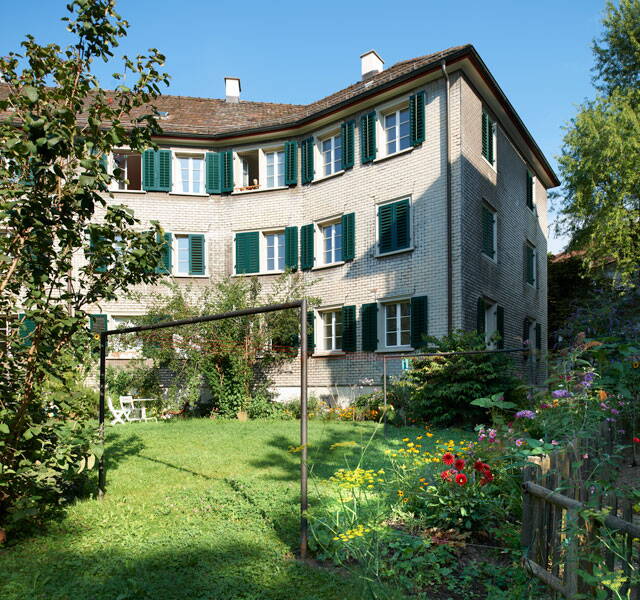 Schindelhäuser, Zürich Wipkingen, Sicht auf Hausecke aus Innenhof, neben Blumengarten